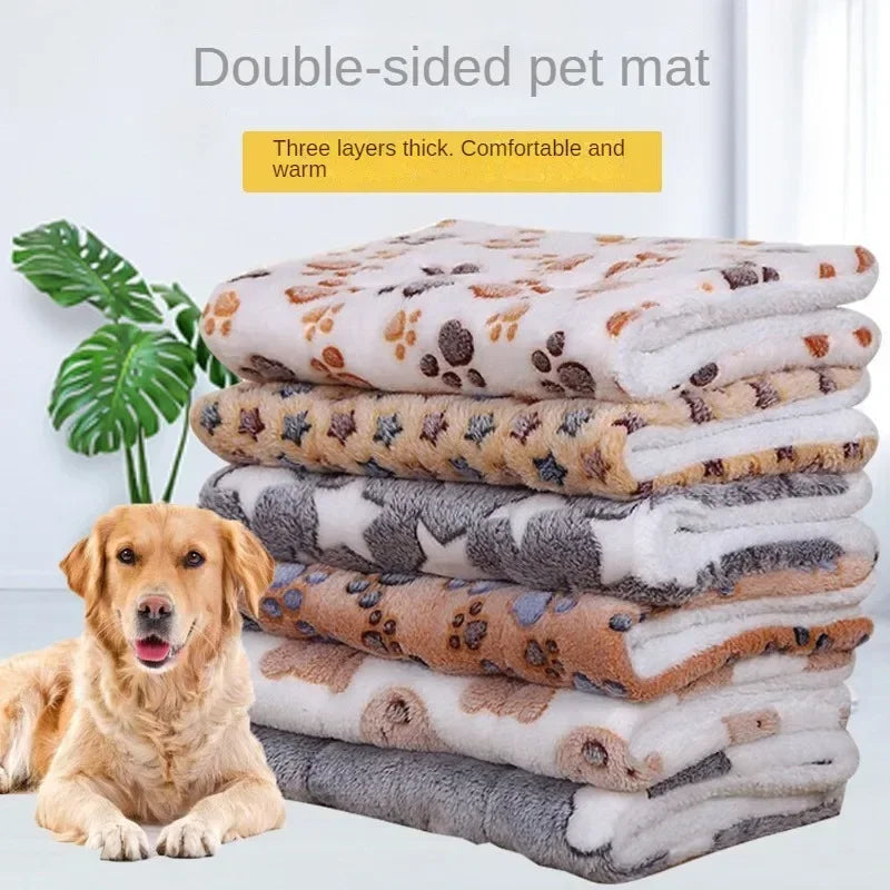 A couple of folded double-sided pet mats stacked on top of each other with a dog sitting beside 